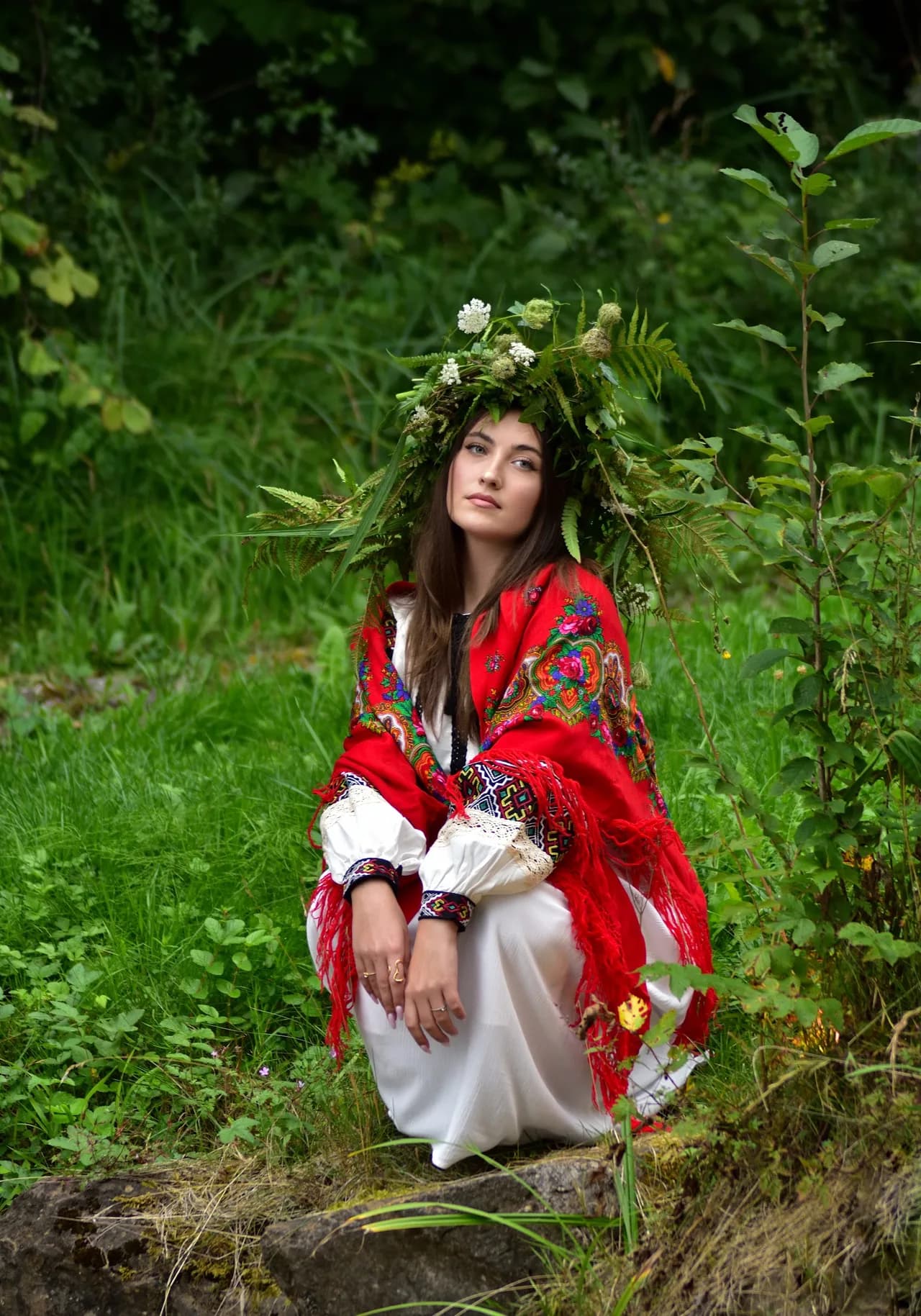 Frau in Tracht mit rotem Tuch und Blumenkranz im Grünen