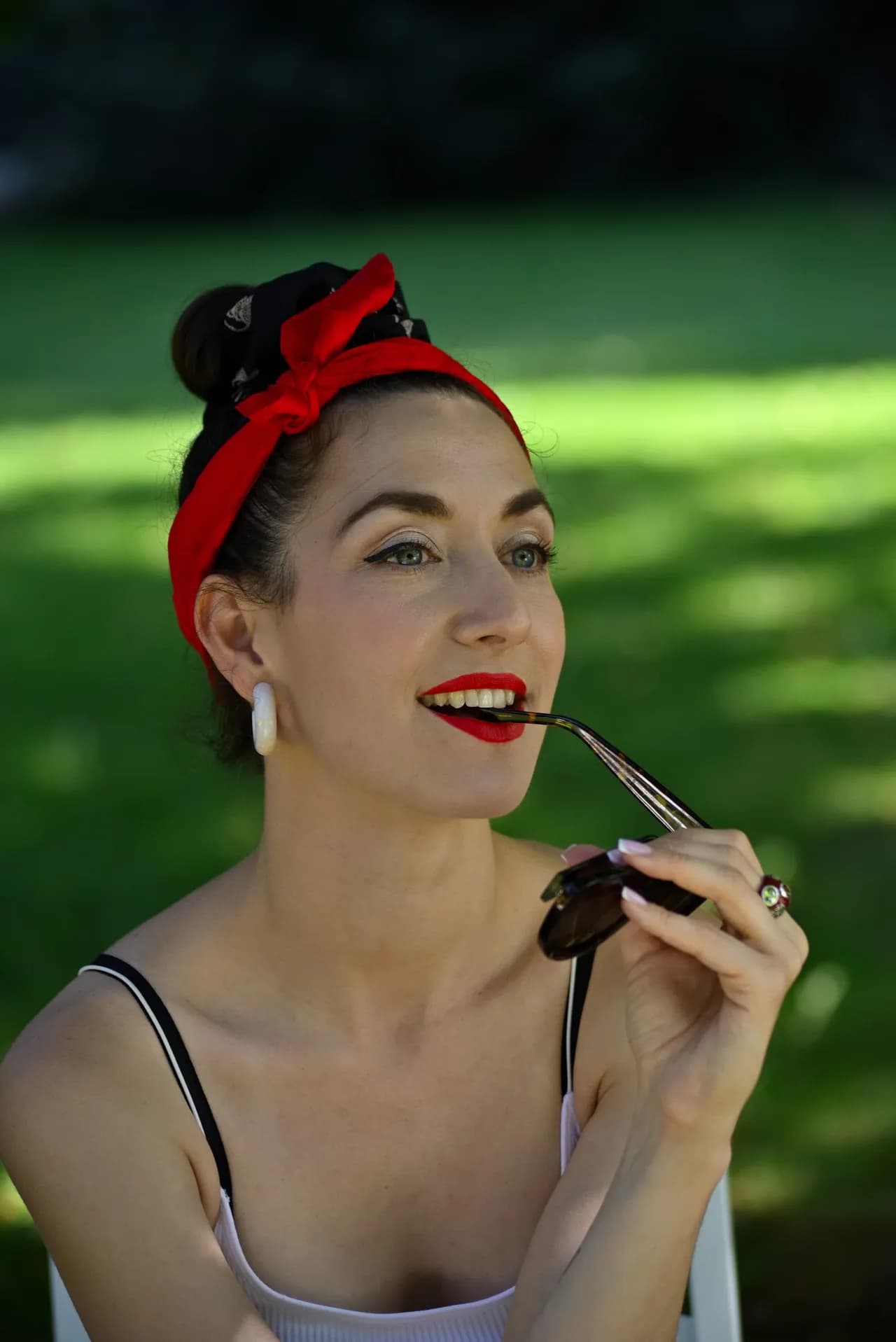 Pin-up-Porträt mit Sonnenbrille in der Hand im Park